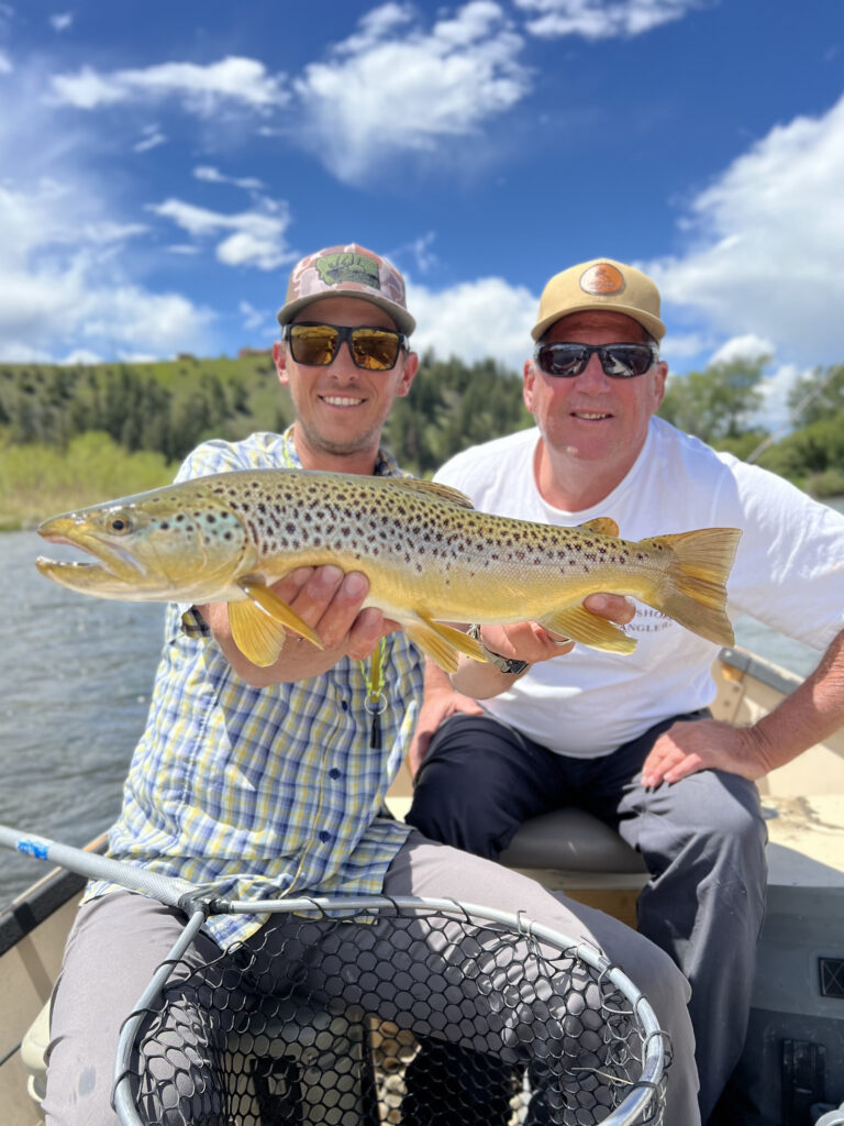 Fly fishing guide and client with a brown trout on the river