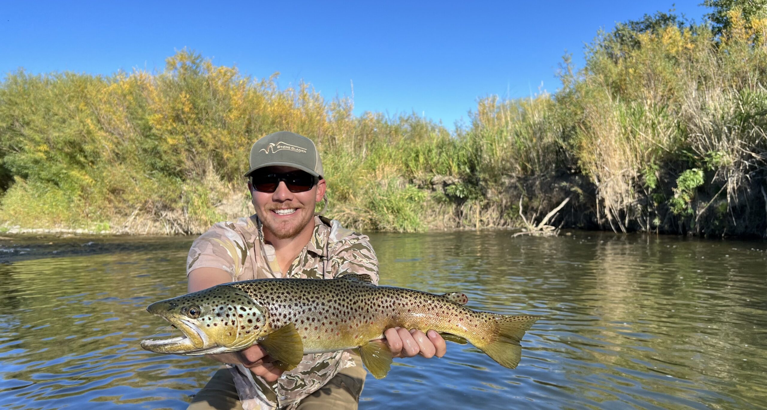 Missoula fly fishing guide Chandler Metcalf holding a large brown trout on a guided fly fishing trip in Missoula, Montana